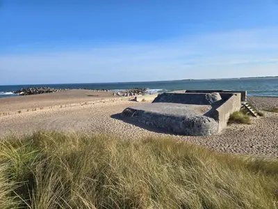 a stone bench on a beach next to the ocean at 6 person holiday home in Thyborøn in Thyborøn