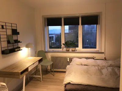 a bedroom with a bed and a desk and a window at Hel lejlighed Thisted Midtby in Thisted