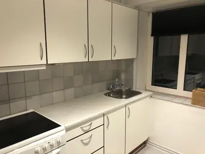 a kitchen with white cabinets and a sink and a window at Hel lejlighed Thisted Midtby in Thisted