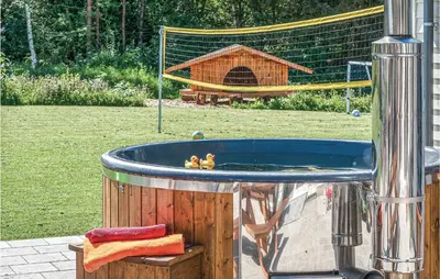 a hot tub with two people in it in a yard at 9 Bedroom Beautiful Home In Spøttrup in Spottrup