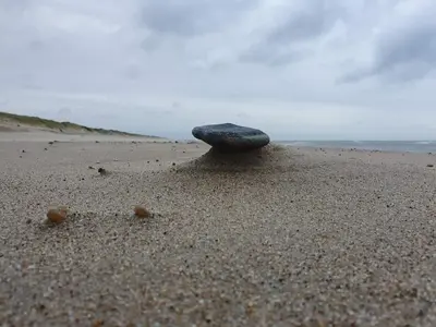 a rock sitting in the sand on a beach at Cozy Beach House Retreat - By Traum Ferienwohnungen in Harboør