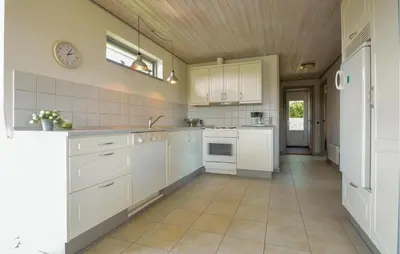 a kitchen with white cabinets and a tile floor at Three-Bedroom Holiday Home In Hurup Thy in Doverodde