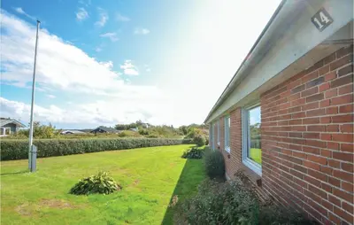 a brick house with a grass yard next to a building at Three-Bedroom Holiday Home In Hurup Thy in Doverodde