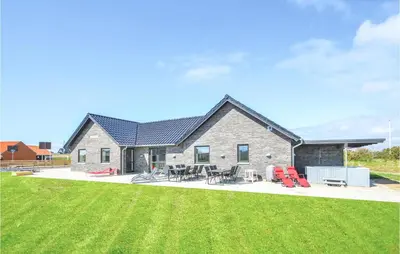 a house with a yard with chairs and tables at Eight-Bedroom Holiday Home In Vestervig in Vestervig