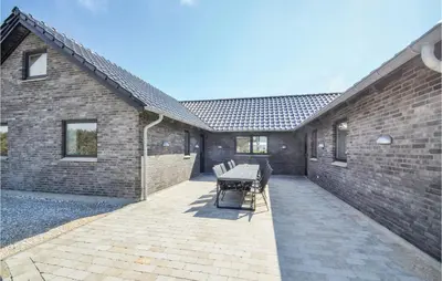 a patio with a table and chairs next to a brick building at Eight-Bedroom Holiday Home In Vestervig in Vestervig