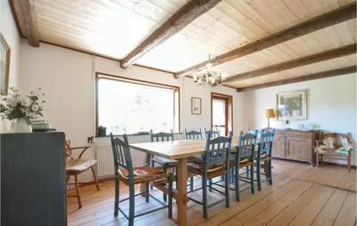 a dining room with a wooden table and chairs at Three-Bedroom Holiday Home In Frostrup in Frøstrup