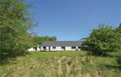 a white house in a field with trees at Three-Bedroom Holiday Home In Frostrup in Frøstrup
