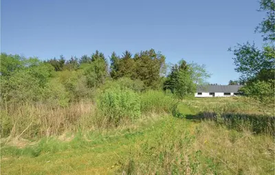 a field with a building in the background and a road at Three-Bedroom Holiday Home In Frostrup in Frøstrup