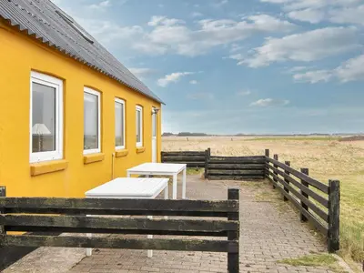 a yellow house with two tables outside of it at 6 person holiday home in Harboøre-By Traum in Harboør