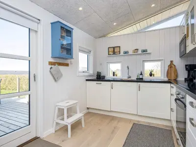 a kitchen with white cabinets and a large window at 6 person holiday home in Lemvig in Lemvig