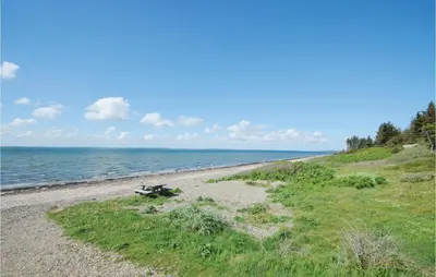 a bench sitting on a beach next to the ocean at Two-Bedroom Holiday Home In Spottrup in Spottrup