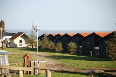 a row of black houses with red roofs at Hytteby – Hanstholm Camping – Thy Feriepark in Hanstholm