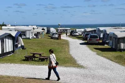 a woman walking down a gravel road with a bunch of tents at Hytteby – Hanstholm Camping – Thy Feriepark in Hanstholm