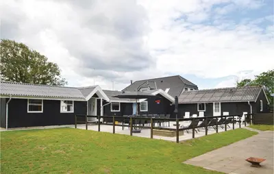 a group of black houses with a grass yard at Five-Bedroom Holiday Home In Blokhus in Blokhus