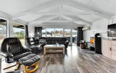 a living room with a black leather couch and a table at Five-Bedroom Holiday Home In Blokhus in Blokhus