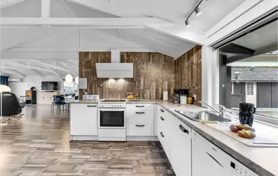 a kitchen with white appliances and wooden walls at Five-Bedroom Holiday Home In Blokhus in Blokhus