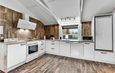 a kitchen with white cabinets and wooden floors at Five-Bedroom Holiday Home In Blokhus in Blokhus