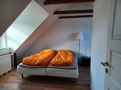 a room with a couch with orange sheets on it at 