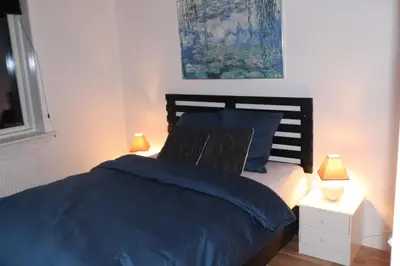 a bedroom with a bed with blue sheets and two lamps at Holstebro Townside House in Holstebro