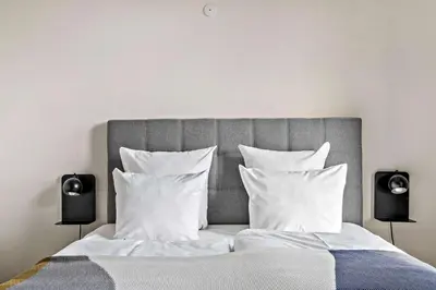 a bedroom with a bed with white pillows and two speakers at Best Western Royal Holstebro in Holstebro