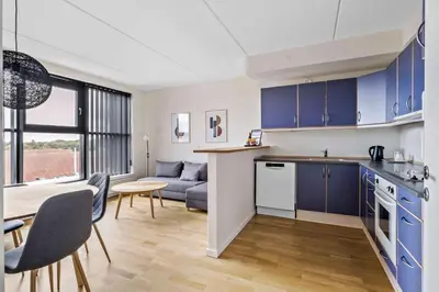 a kitchen and living room with blue cabinets and a table at Best Western Royal Holstebro in Holstebro