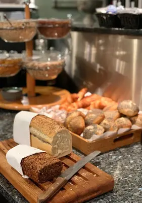 a counter with bread and a cutting board with a knife at Hotel Schaumburg in Holstebro