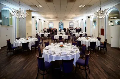 a banquet hall with white tables and chairs and chandeliers at Hotel Schaumburg in Holstebro