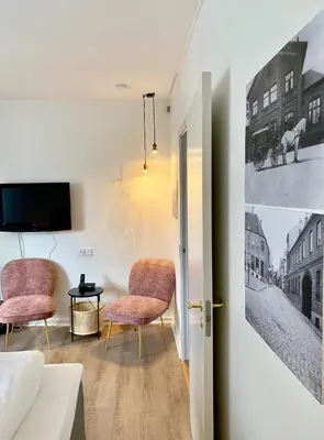 a living room with two chairs and a tv at Hotel Schaumburg in Holstebro