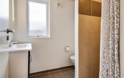 a bathroom with a sink and a toilet and a window at Nice Home In Spøttrup With Sauna in Spottrup