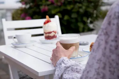 a person sitting at a table with a cup of coffee at Tambohus Kro & Badehotel in Hvidbjerg