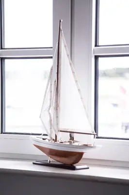 a wooden toy boat sitting on a table in a window at Tambohus Kro & Badehotel in Hvidbjerg