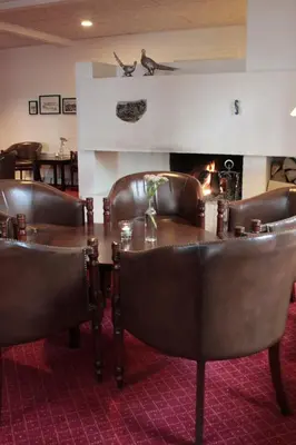 a dining room with a table and chairs and a fireplace at Tambohus Kro & Badehotel in Hvidbjerg