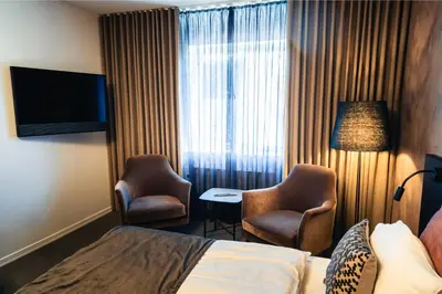 a hotel room with a bed and two chairs and a television at Struer Grand Hotel in Struer
