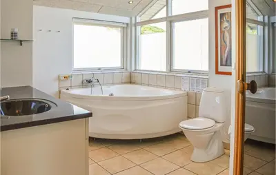 a bathroom with a tub and a toilet and a sink at Three-Bedroom Holiday Home In Harboore in Harboør