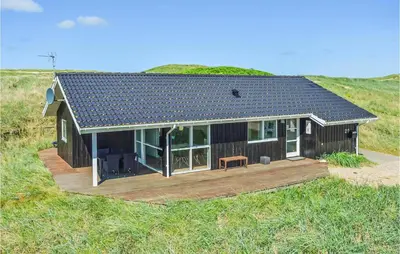 a small house with a deck in a field at Three-Bedroom Holiday Home In Harboore in Harboør