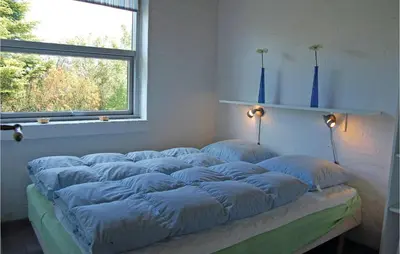 a bed with blue pillows on it in a room with a window at Five-Bedroom Holiday Home In Thisted in Thisted
