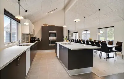 a large kitchen with a long island with a table and chairs at Lovely Home In Spøttrup With Sauna in Spottrup