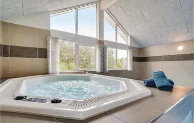a large bath tub in a room with a large window at Lovely Home In Spøttrup With Sauna in Spottrup