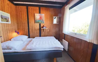 a bed in a wooden room with a window at Three-Bedroom Holiday Home In Hurup Thy in Doverodde