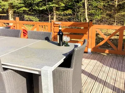 a table with a bottle of wine on a deck at Spacious Family Retreat - By Traum Ferienwohnungen in Skals