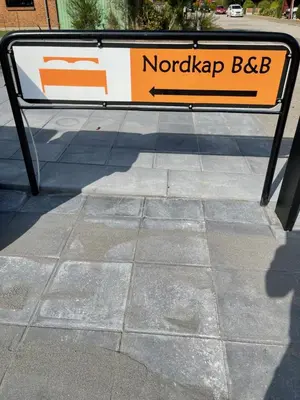 a sign sitting on the side of a sidewalk at Nordkap Bed & Bath in Holstebro