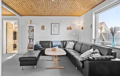 a living room with a black couch and a table at Four-Bedroom Holiday Home In Thyboron in Thyborøn