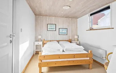a bedroom with a bed with white pillows on it at Four-Bedroom Holiday Home In Thyboron in Thyborøn
