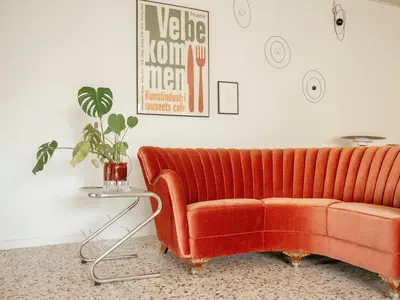 an orange couch in a living room with a table at Containerhus 18b in Harboør