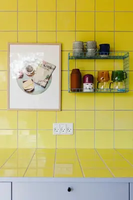 a picture hanging on a yellow tiled wall with a shelf at Containerhus 18b in Harboør