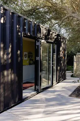 a black shipping container with doors on a sidewalk at Containerhus 18b in Harboør