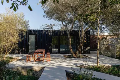 a black house with a wooden table and some trees at Containerhus 18b in Harboør