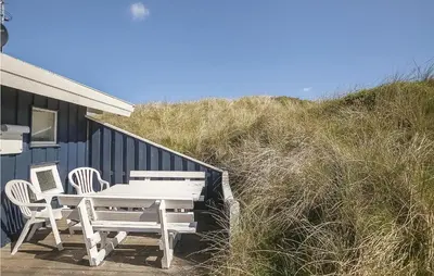a picnic table and chairs next to a blue building at Beautiful Home In Blokhus With Wifi in Blokhus