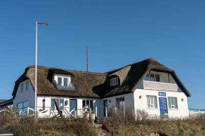 a house with a thatched roof on the beach at Klitmøller Hotel in Klitmøller