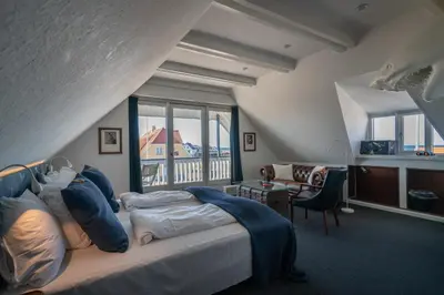 a bedroom with a large bed and a balcony at Klitmøller Hotel in Klitmøller